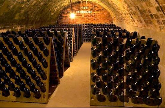 Bottles resting in wooden riddling racks beneath the brick vaults of the Gramona cellar