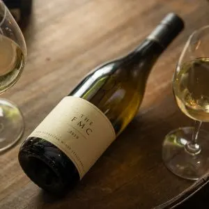 A bottle of The FMC Chenin Blanc beside two glasses