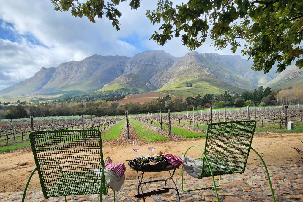Two chairs and a table overlooking the vineyard and mountains