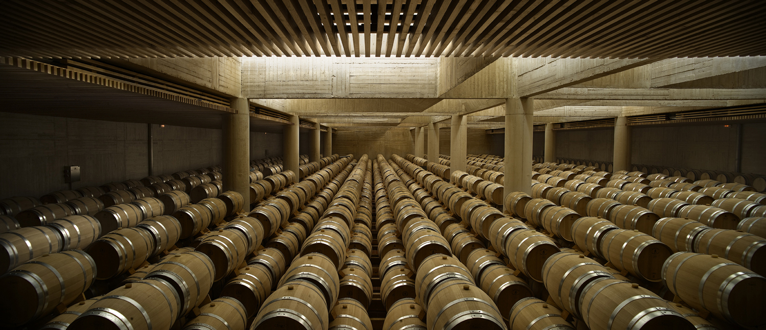 Long rows of barrels resting beneath the concrete beams of the Pago de Carraovejas cellar