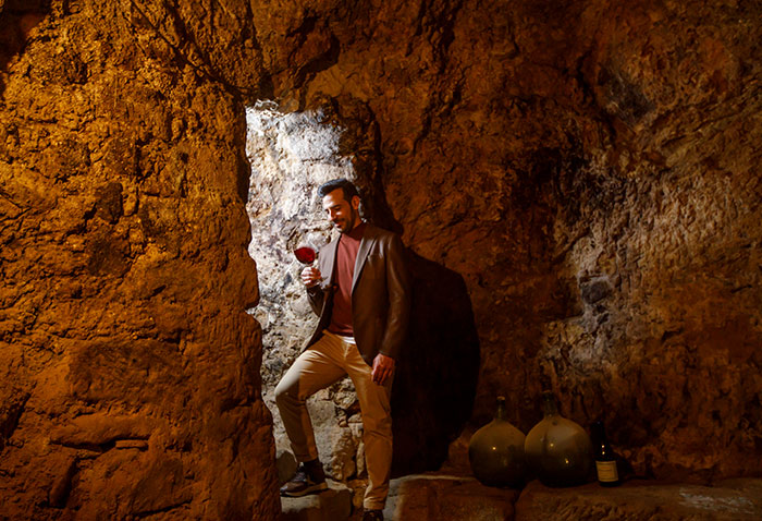 Eduardo Eguren tasting red wine in a small stone cellar