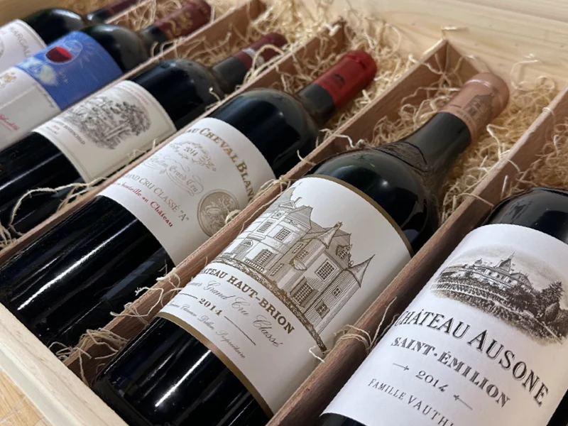 A wooden crate of classic Bordeaux bottles packed in straw