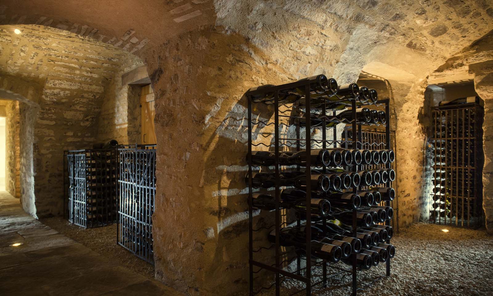 Bottles resting in iron racks beneath stone vaults