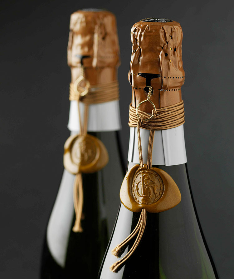 Two Gramona sparkling wine bottles with gold foil and the family crest